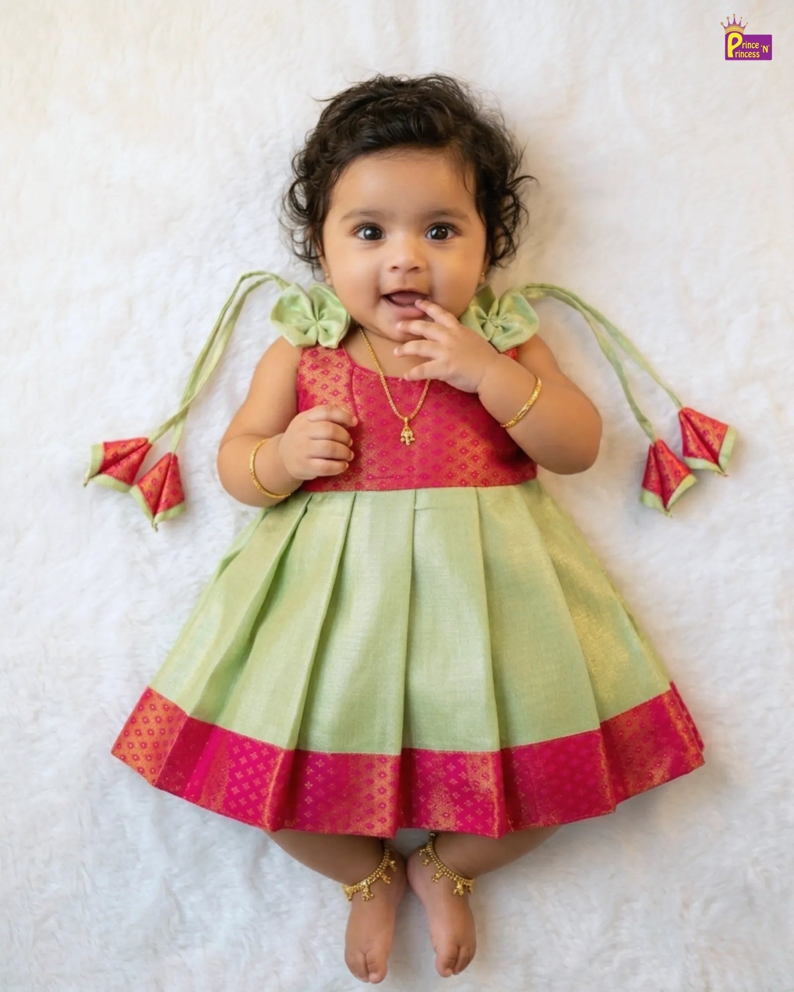 Baby wearing a colorful traditional outfit with a red and green dress on a white background