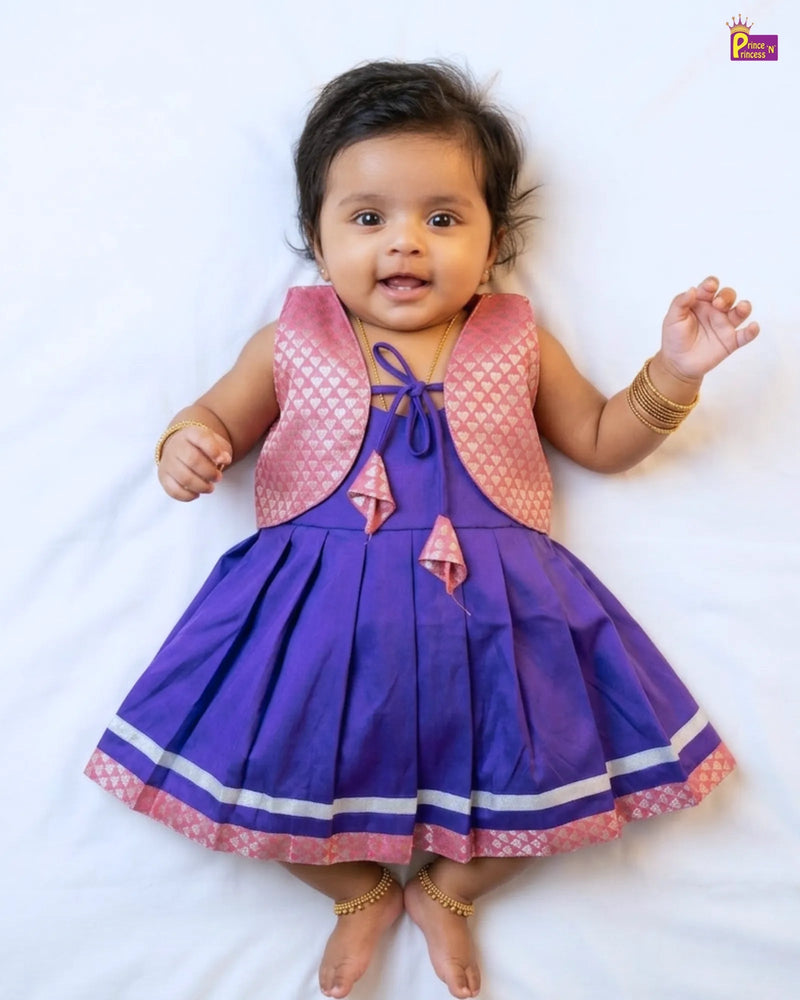 Baby wearing a purple dress with a pink vest on a white background