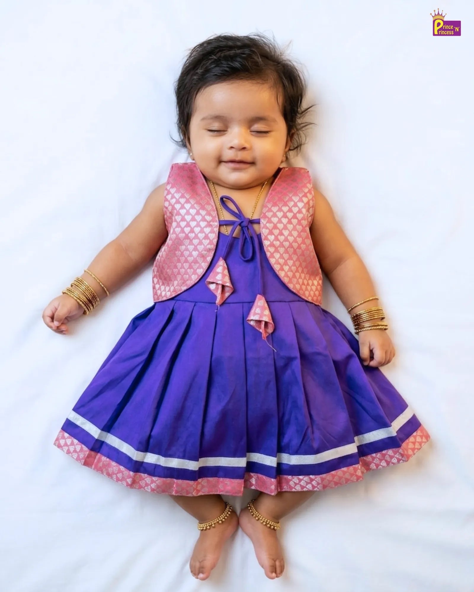 Baby wearing a purple and pink dress with a white background