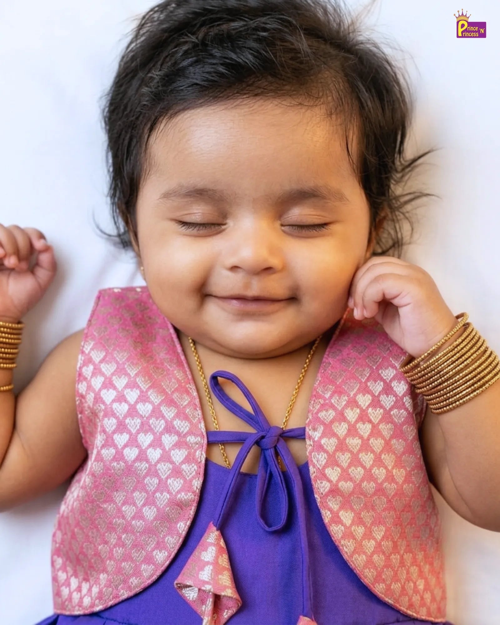 Baby wearing a pink and gold outfit with a white background
