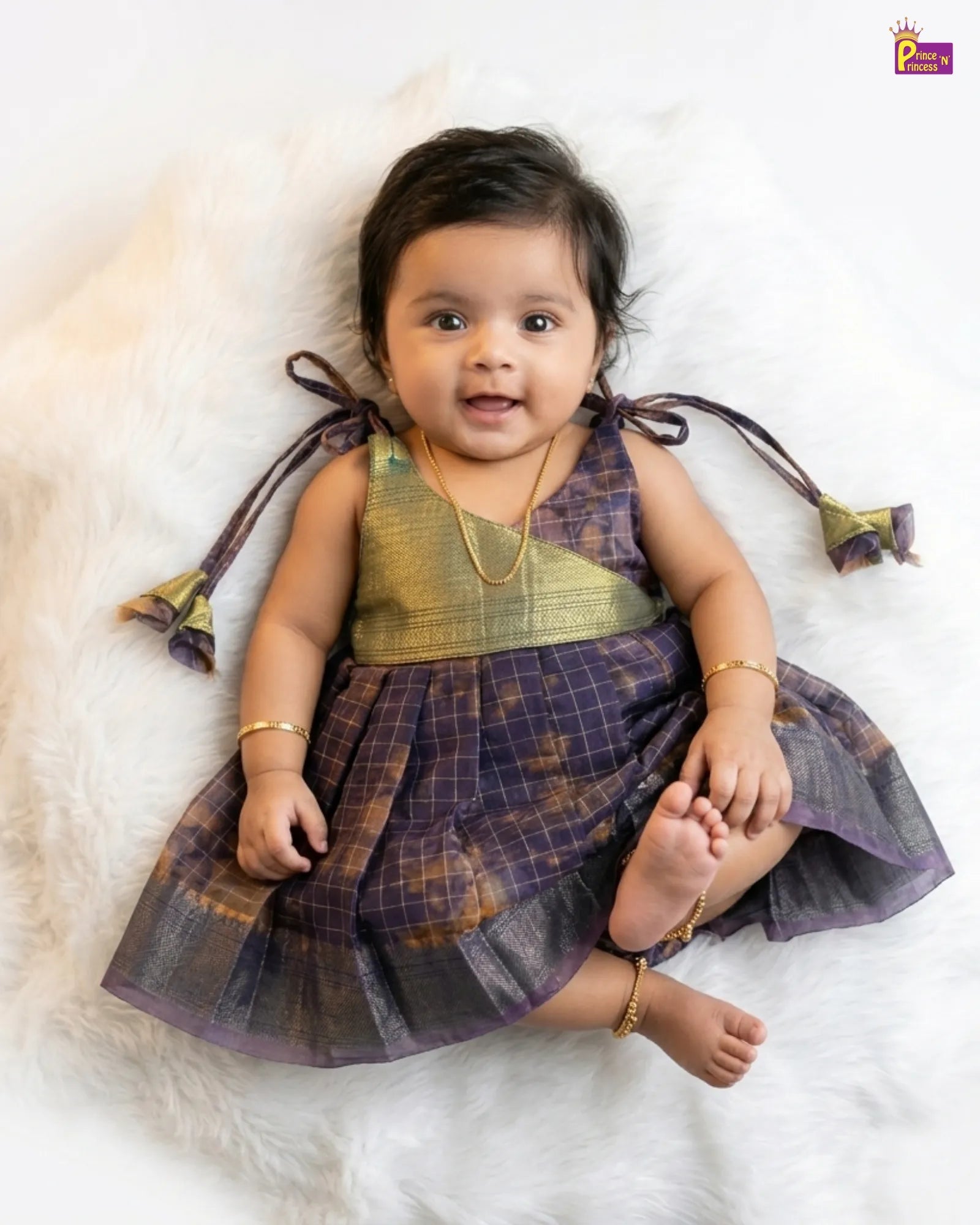 Baby wearing a traditional outfit with a checkered pattern on a white background