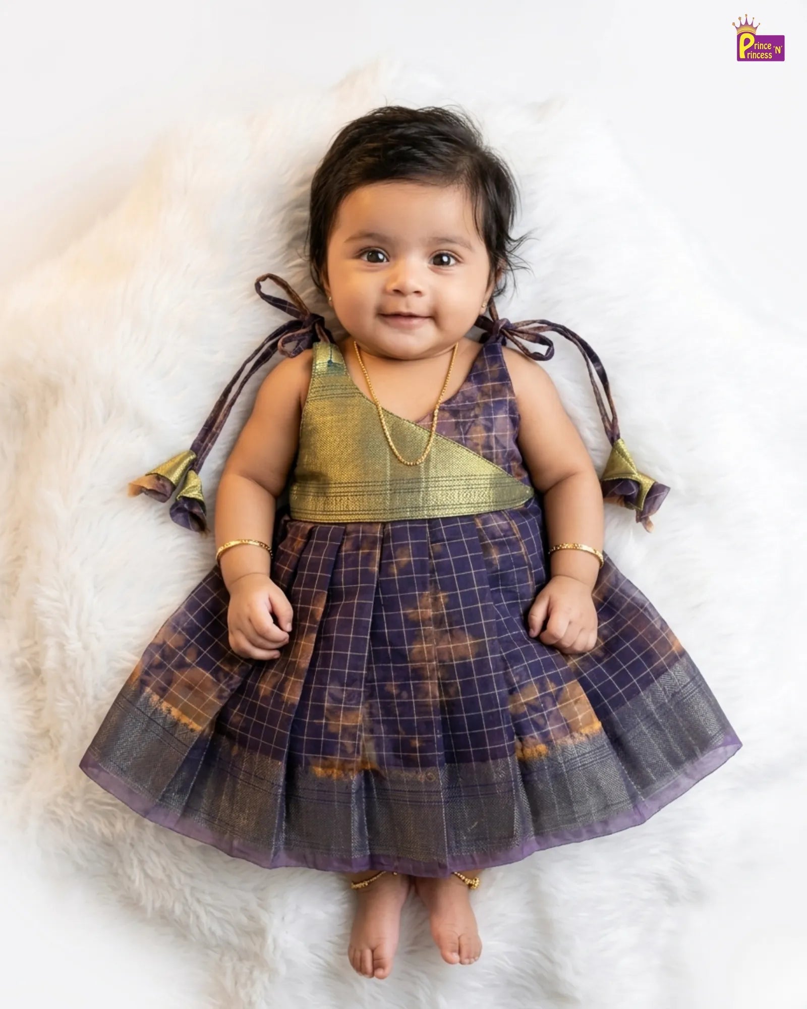 Baby wearing a traditional outfit with a checkered pattern on a white background