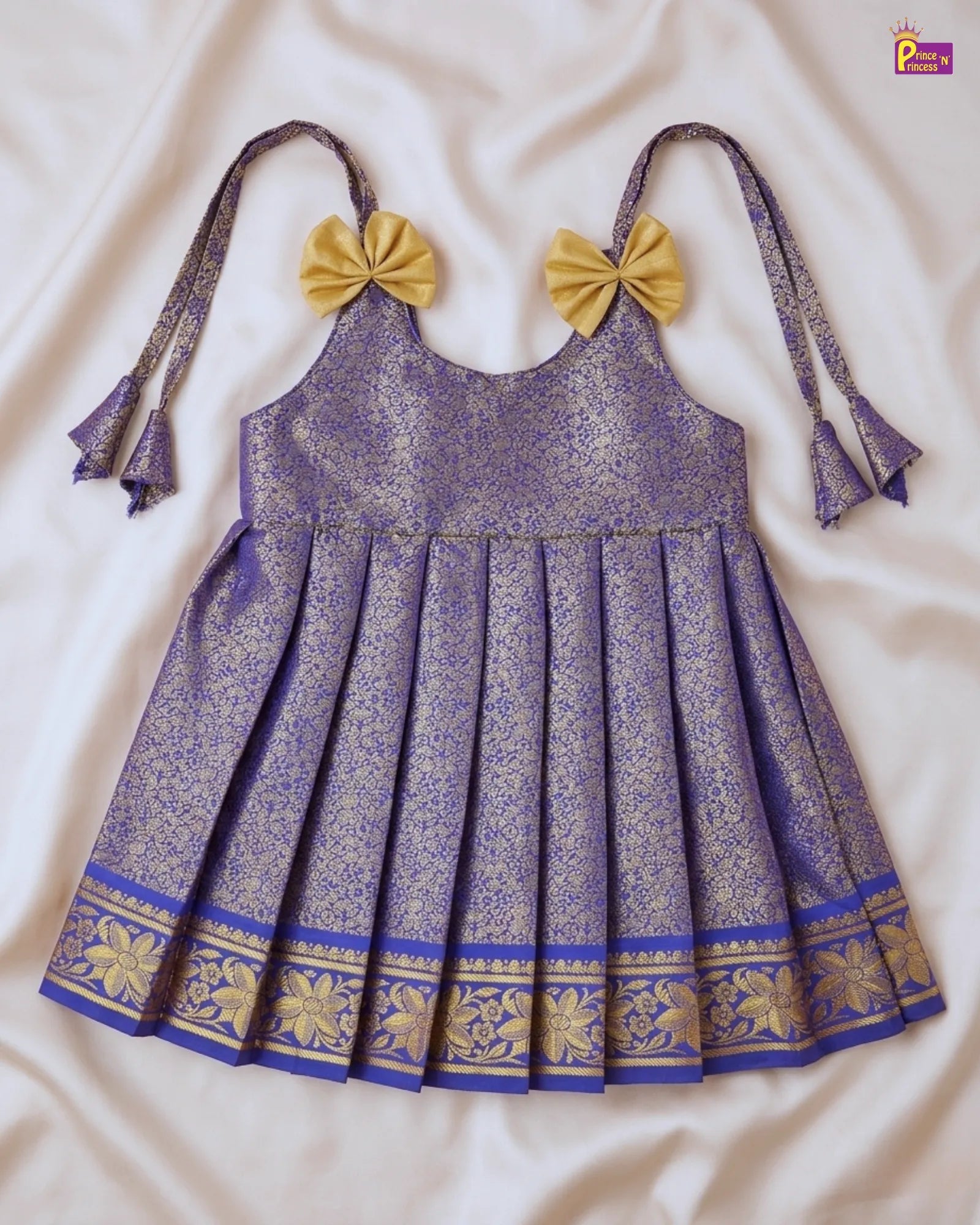 Purple dress with gold accents and yellow bows on a white fabric background