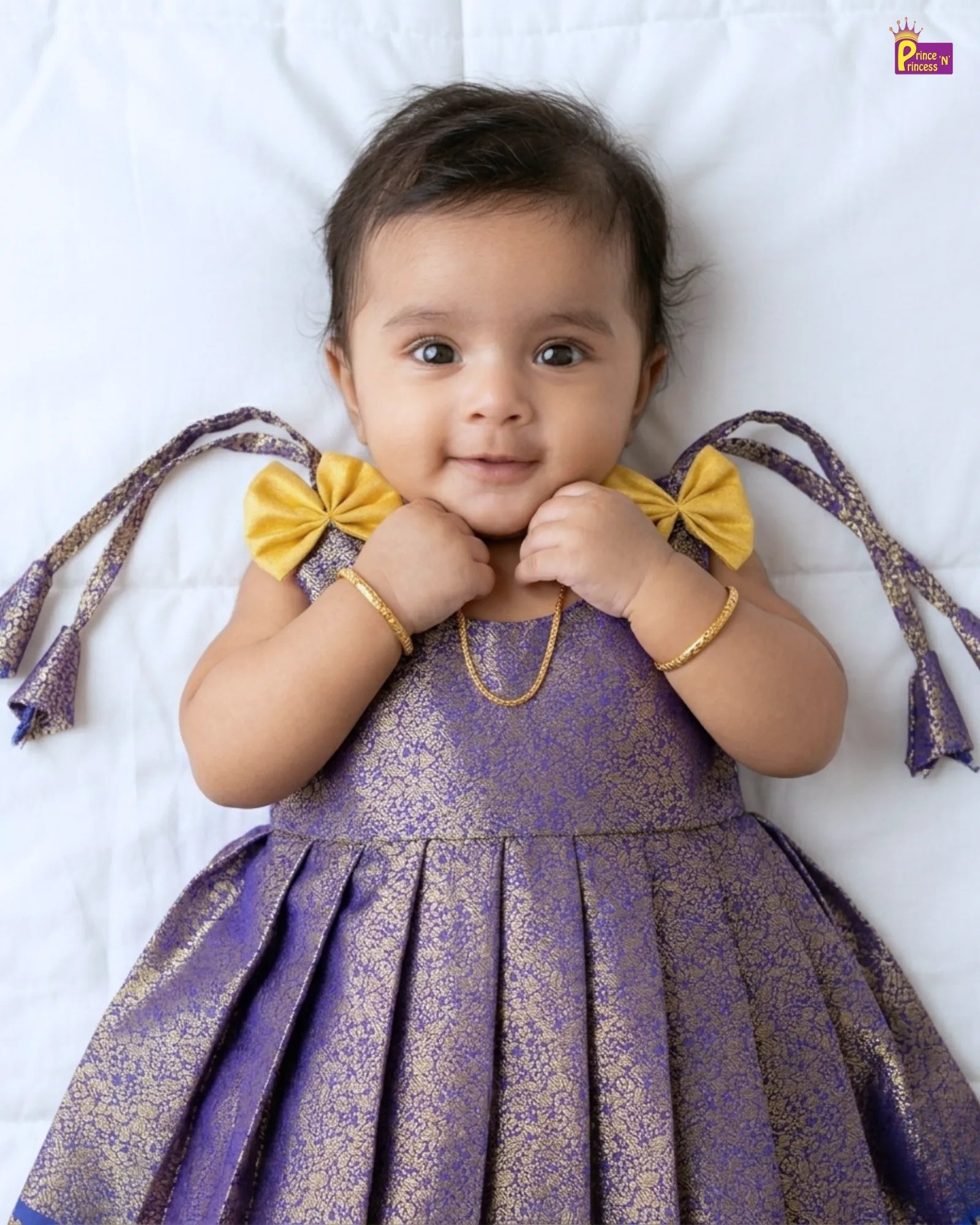 Baby wearing a purple dress with yellow bows on a white background