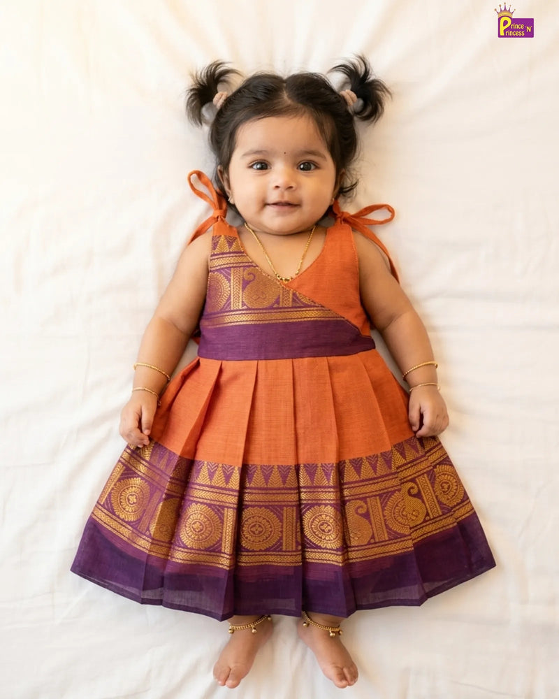 Baby wearing an orange and purple traditional dress on a white background