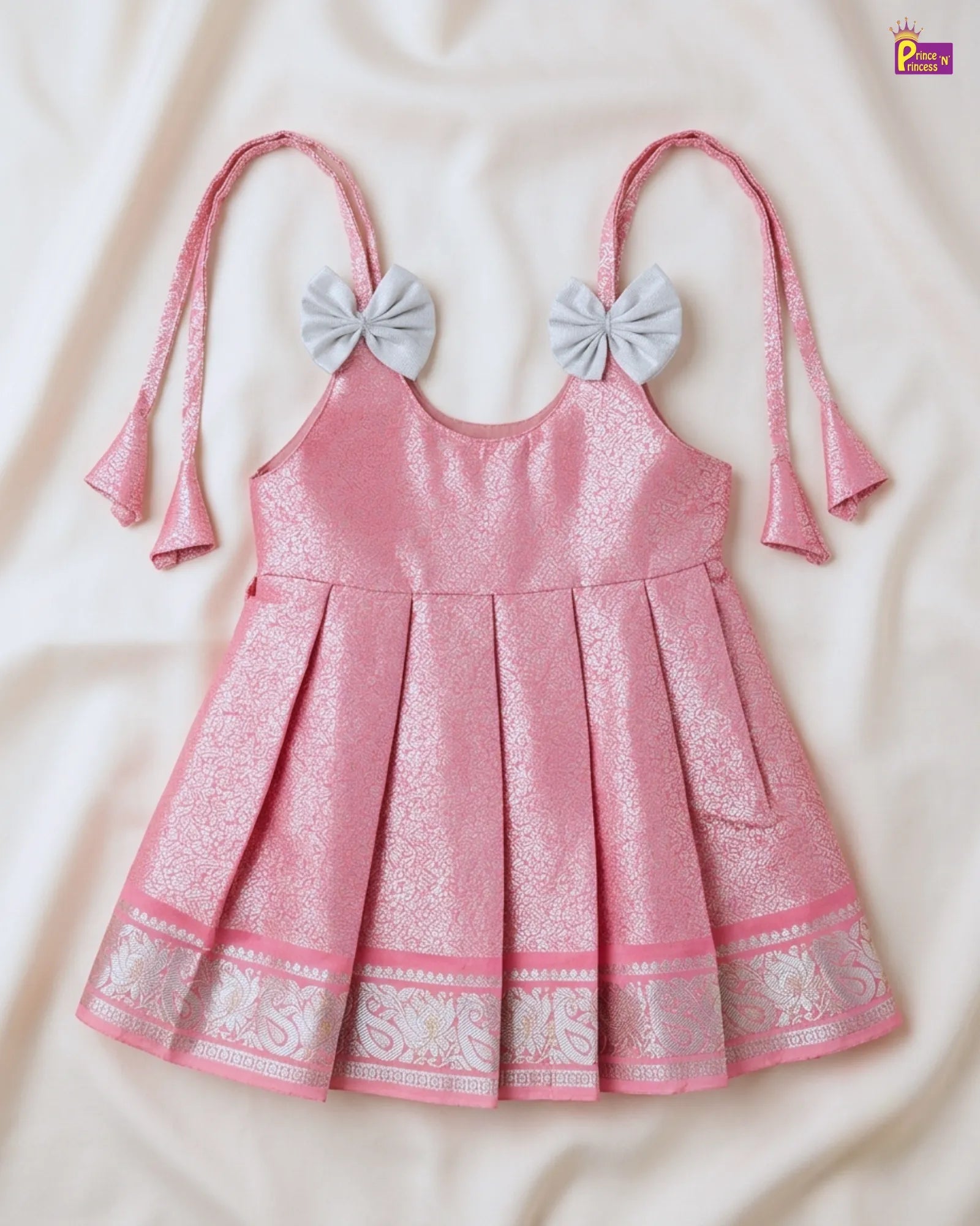 Pink dress with decorative bows on straps on a beige background