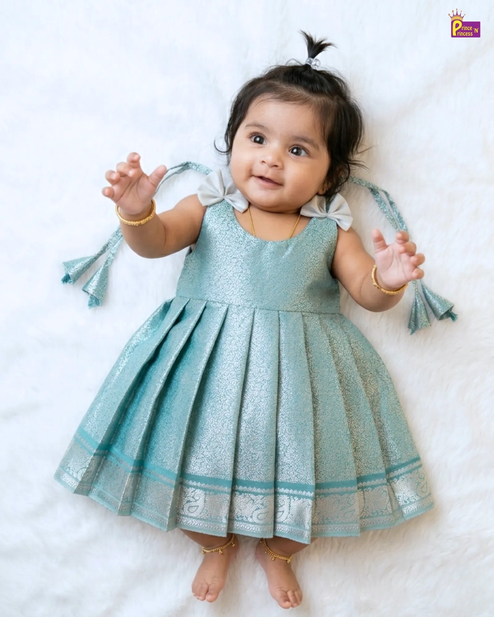 Baby wearing a light blue dress with decorative elements on a white background