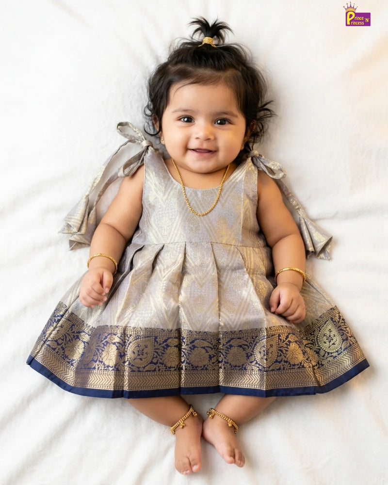 Newborn baby girl in silver grey Banarasi silk frock with gold brocade weave and wide navy blue Kanjivaram zari border by Prince N Princess