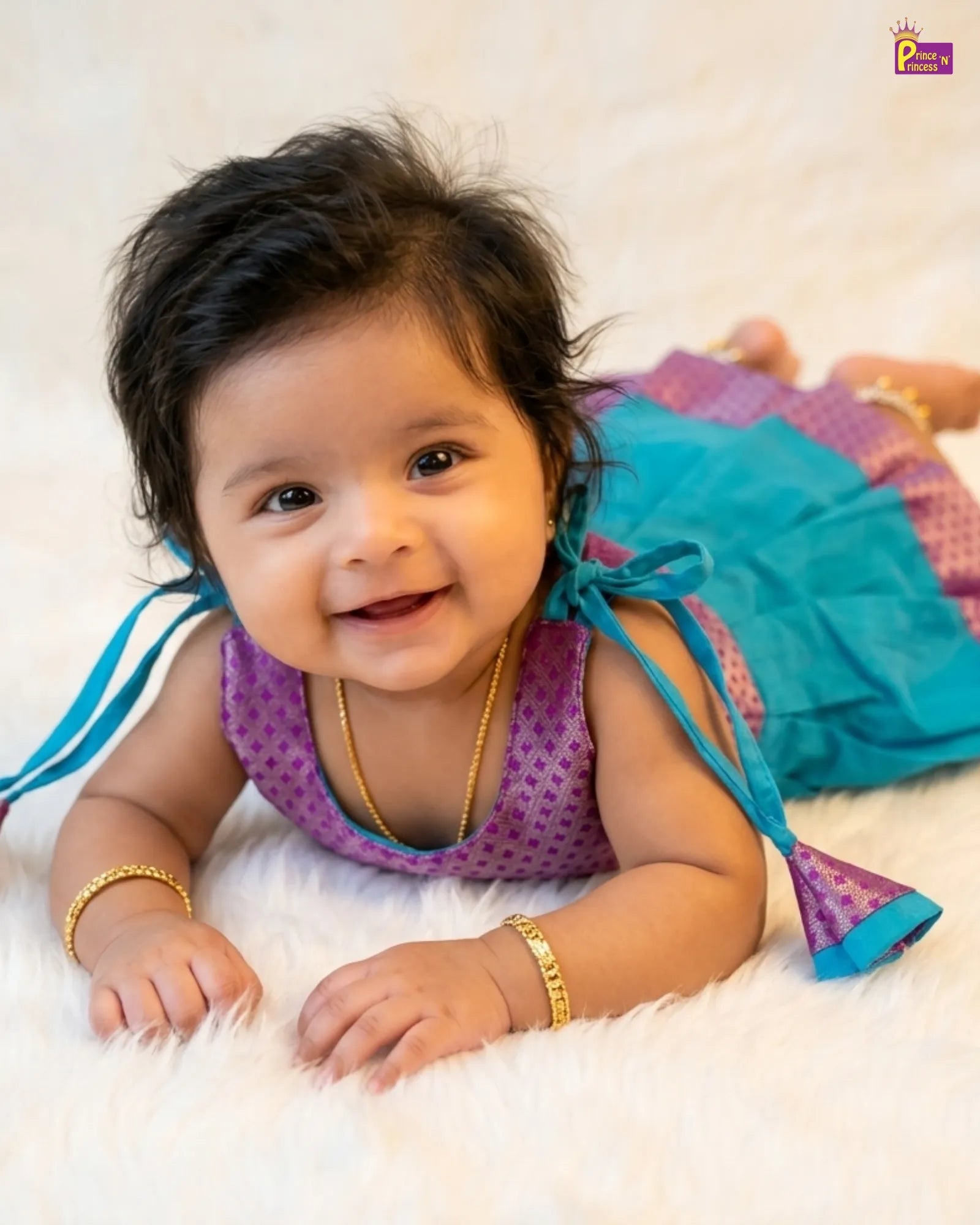 Baby wearing a colorful outfit with a blue and purple dress on a white background