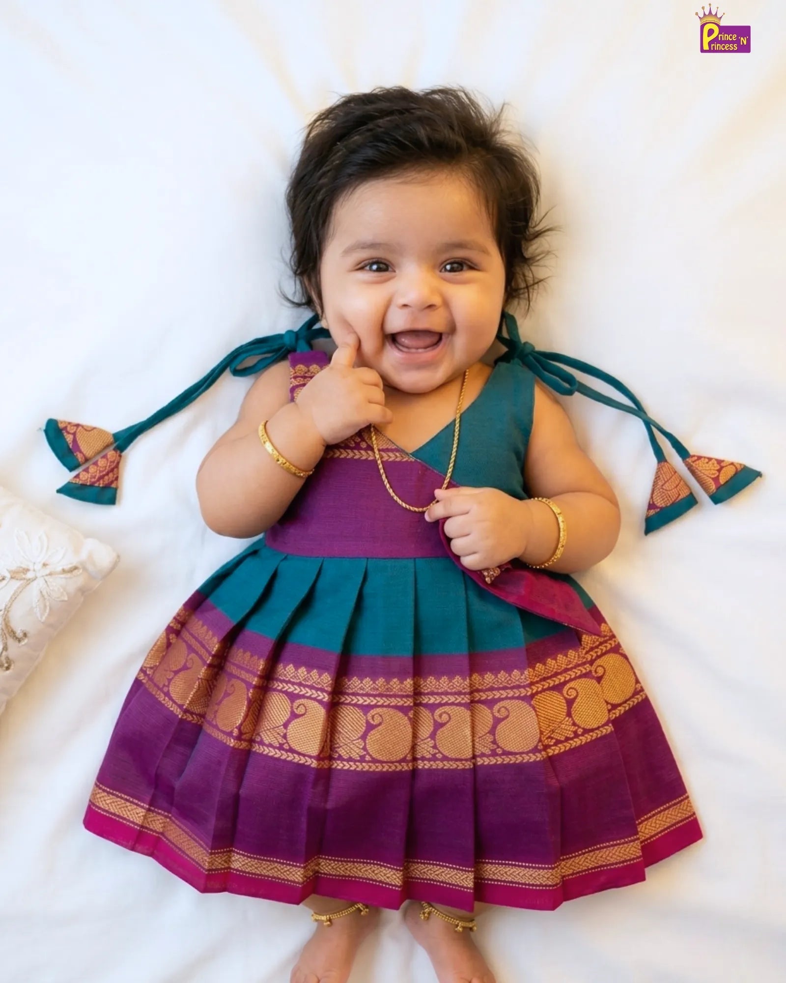 Child wearing a traditional outfit with a purple and green dress on a white background