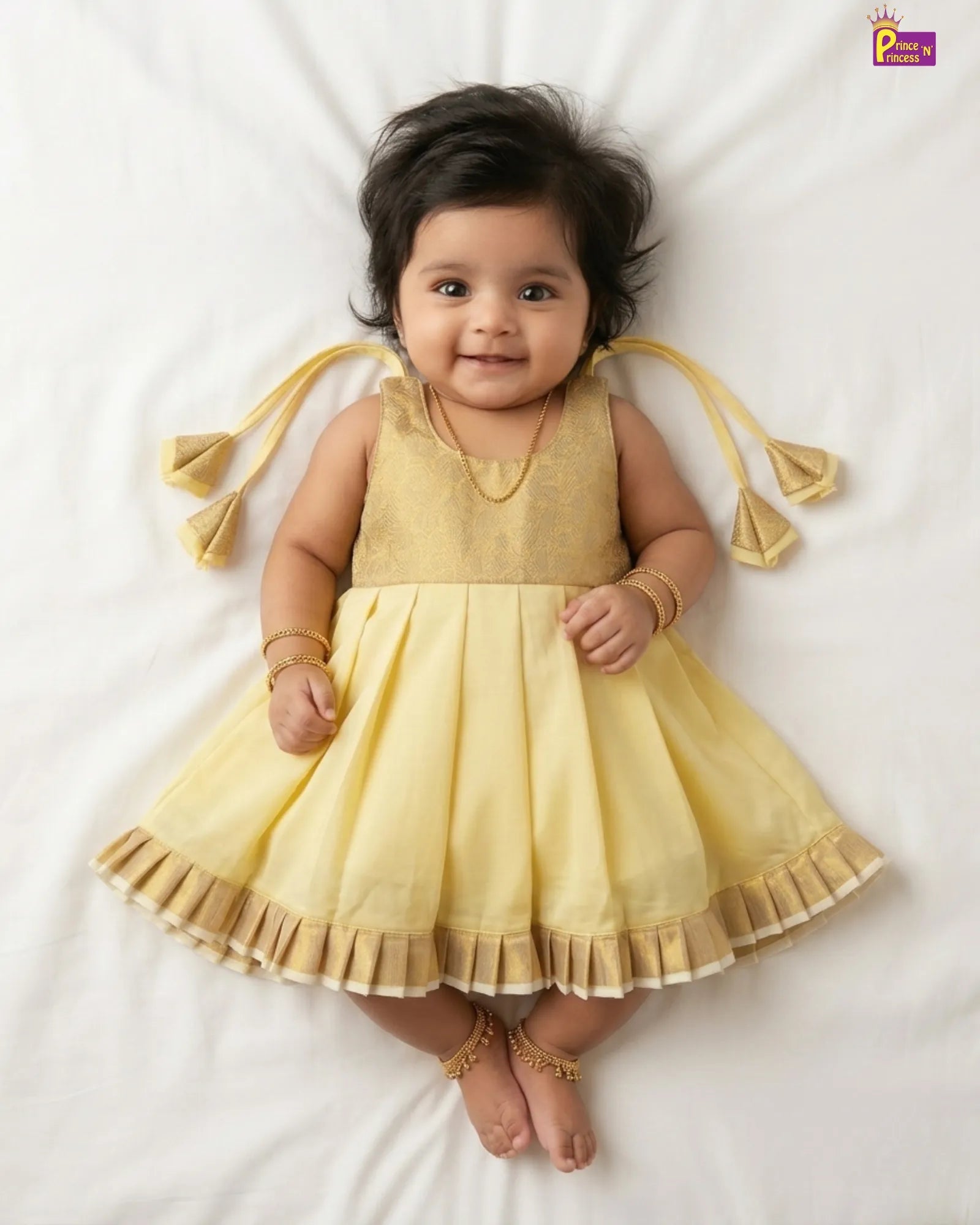 Baby wearing a yellow dress with tassels on a white background
