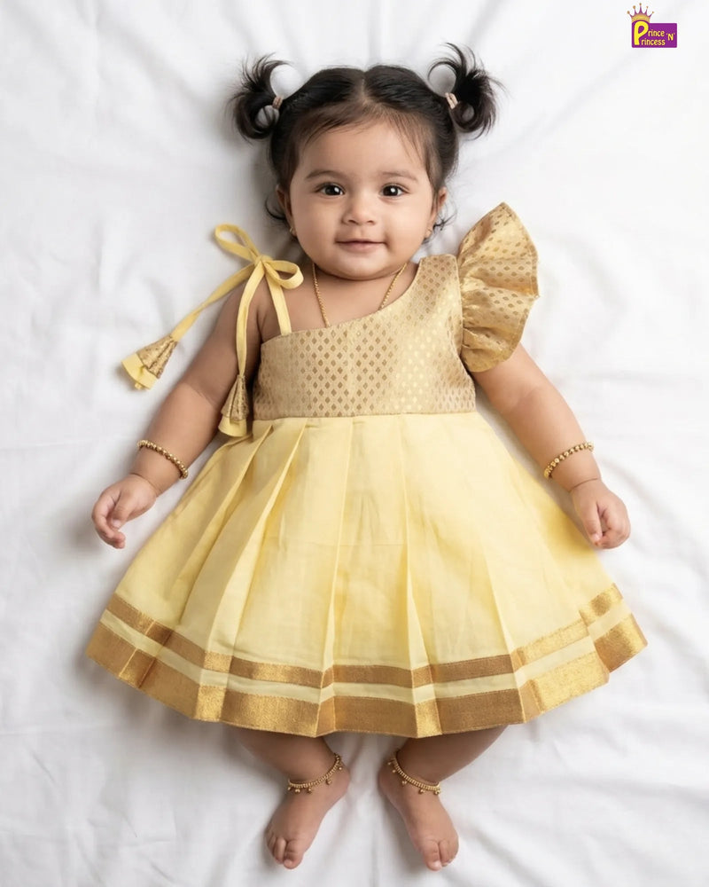 Newborn baby girl in pale yellow silk pattu frock with gold brocade bodice one-shoulder ruffle and double gold stripe border by Prince N Princess