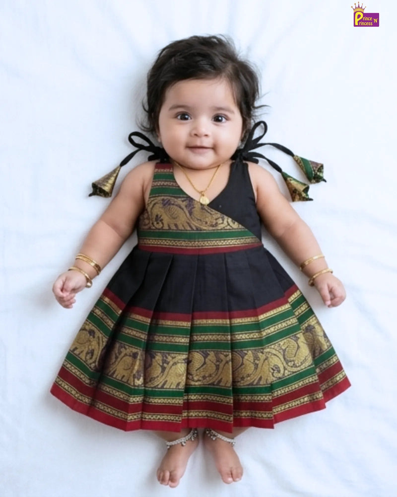 Baby wearing a traditional dress with black, green, and red colors on a white background