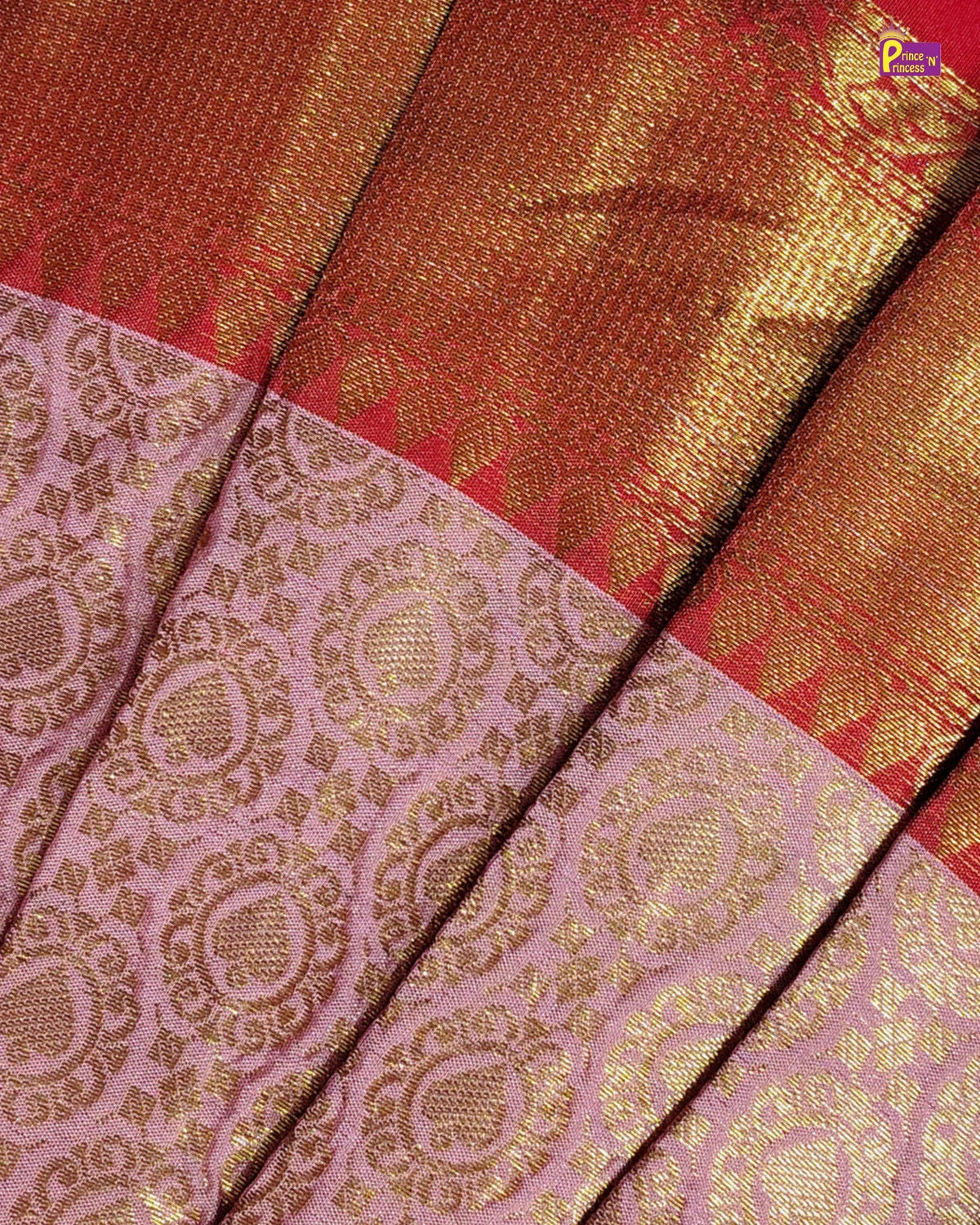 A close-up of a traditional Indian silk saree fabric, showing a pink body with intricate gold zari floral patterns and a wide golden-red border.