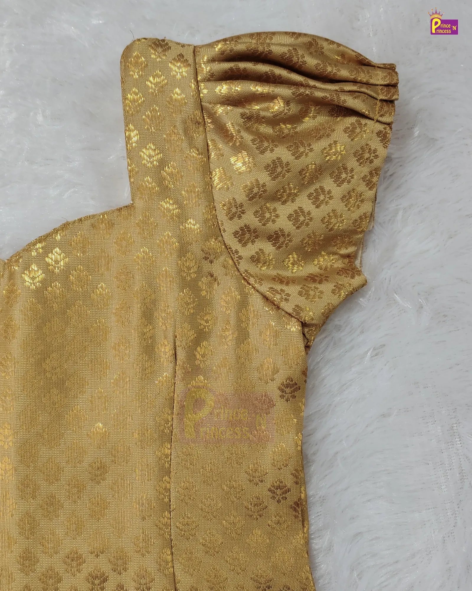 A close-up of a gold brocade fabric with a floral pattern, draped on a white faux fur background.
