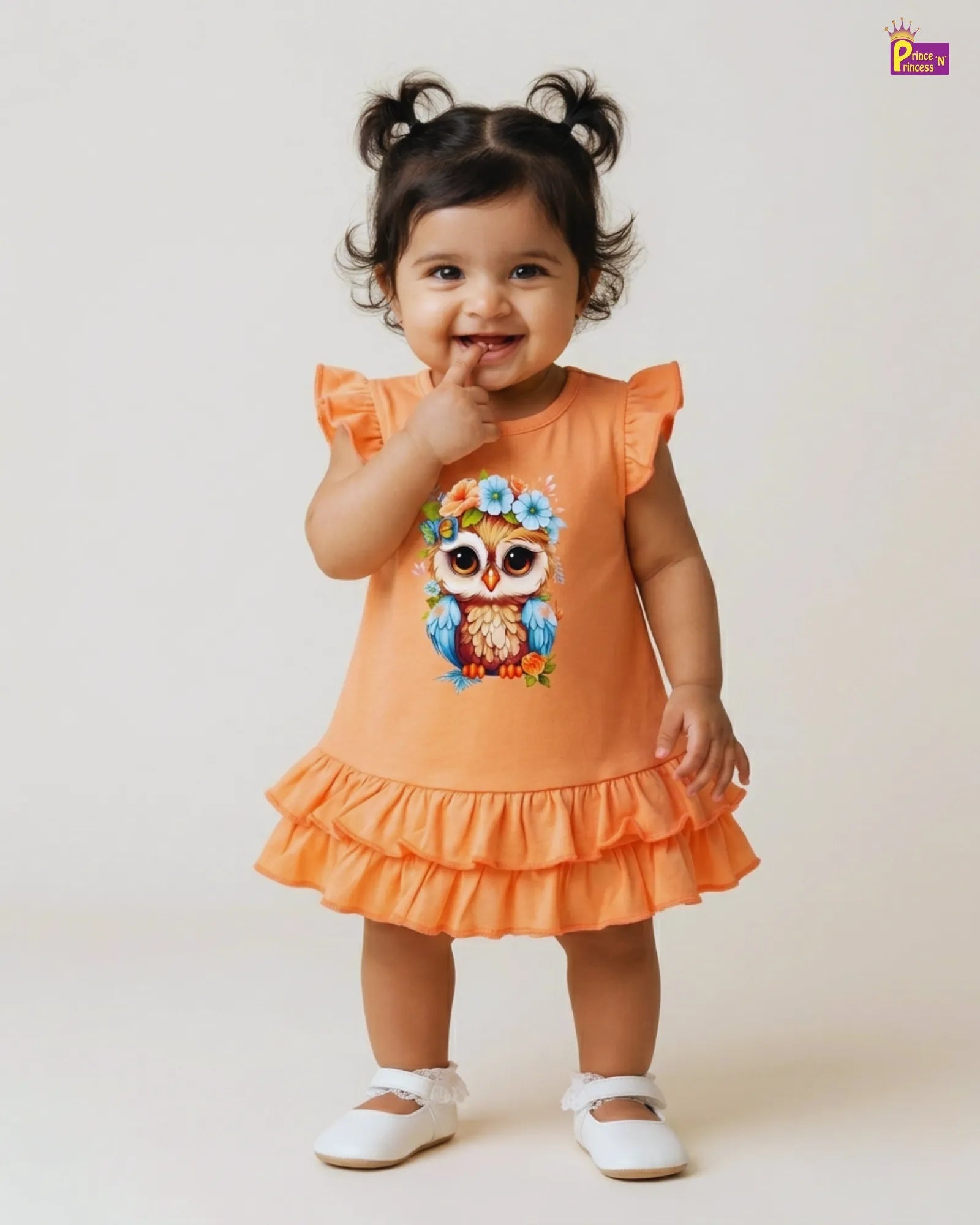 Child wearing an orange dress with a colorful owl design on a white background