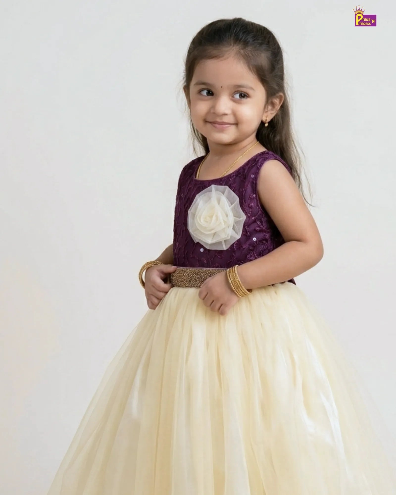 Young girl in a purple top and beige skirt with a white flower detail on a white background