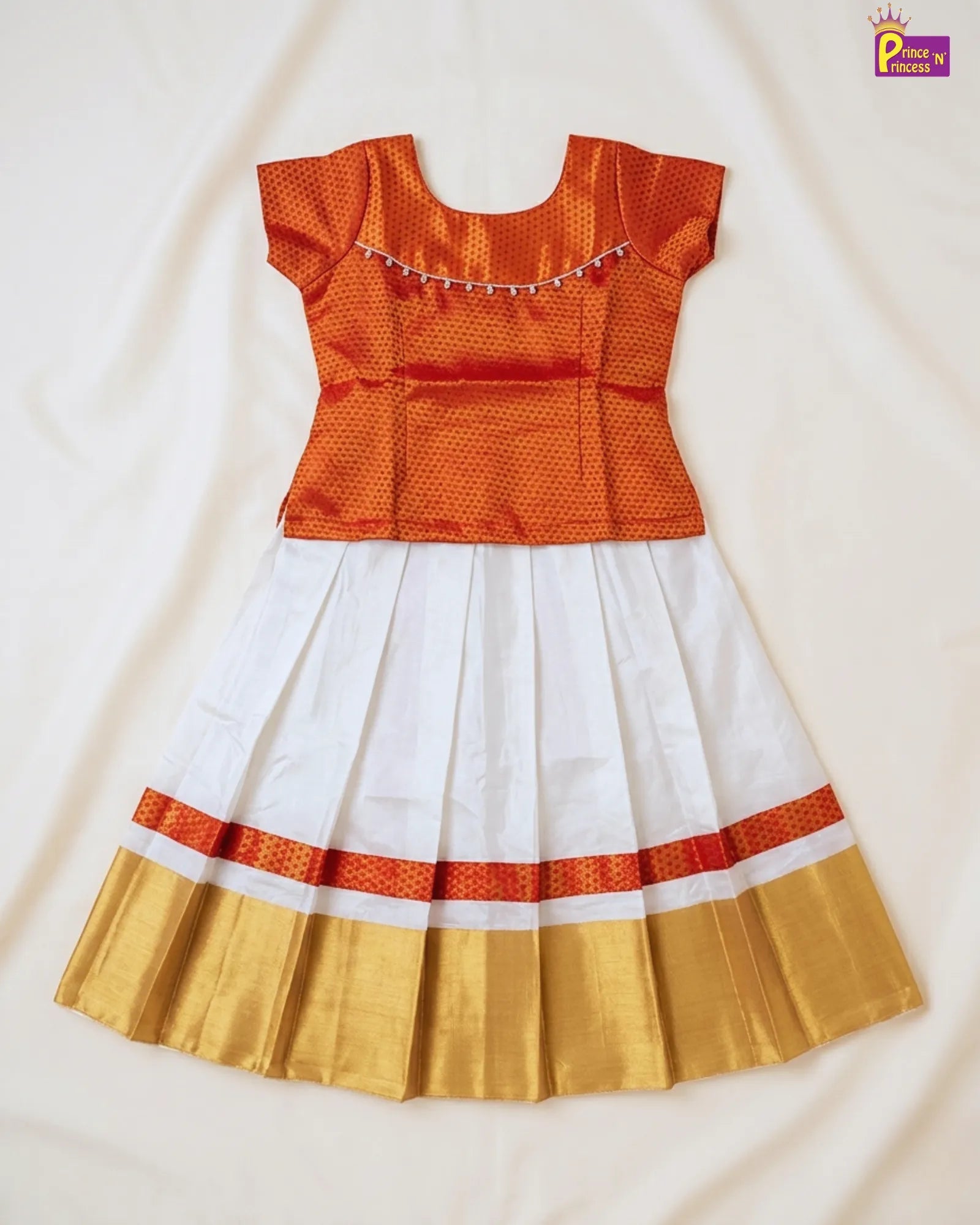 Traditional outfit with orange top, white skirt, and gold border on a light background