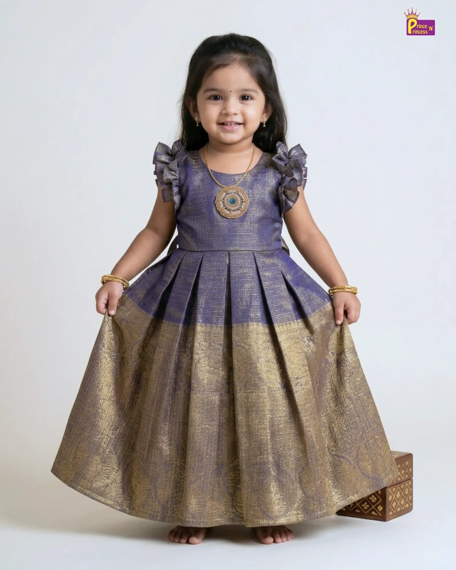 Young girl wearing a traditional outfit with a purple top and gold skirt on a white background
