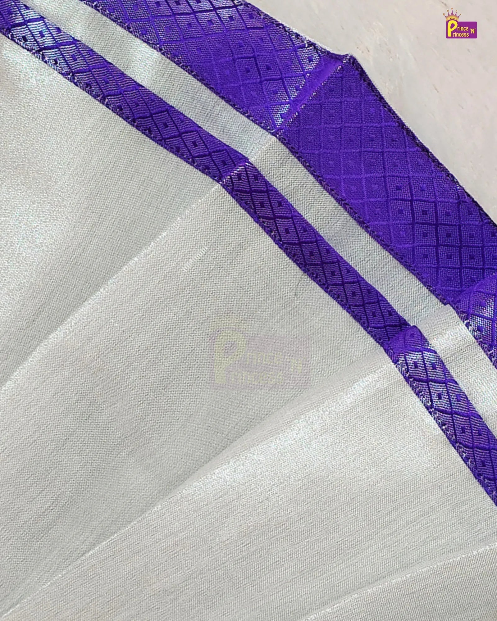 A close-up of a white or off-white fabric with a prominent purple border featuring a woven geometric pattern.