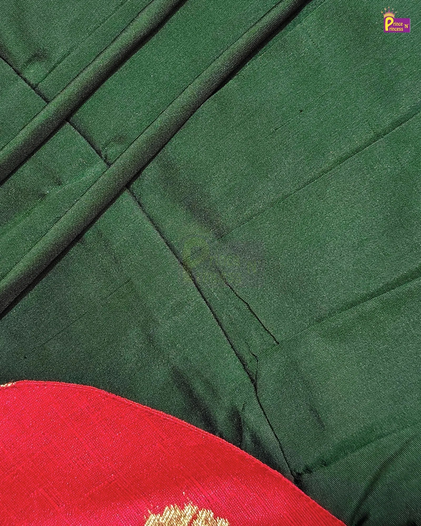 Close-up of a dark green fabric garment with diagonal stitched paneling and a bright red fabric section with gold embroidery visible in the lower left corner.