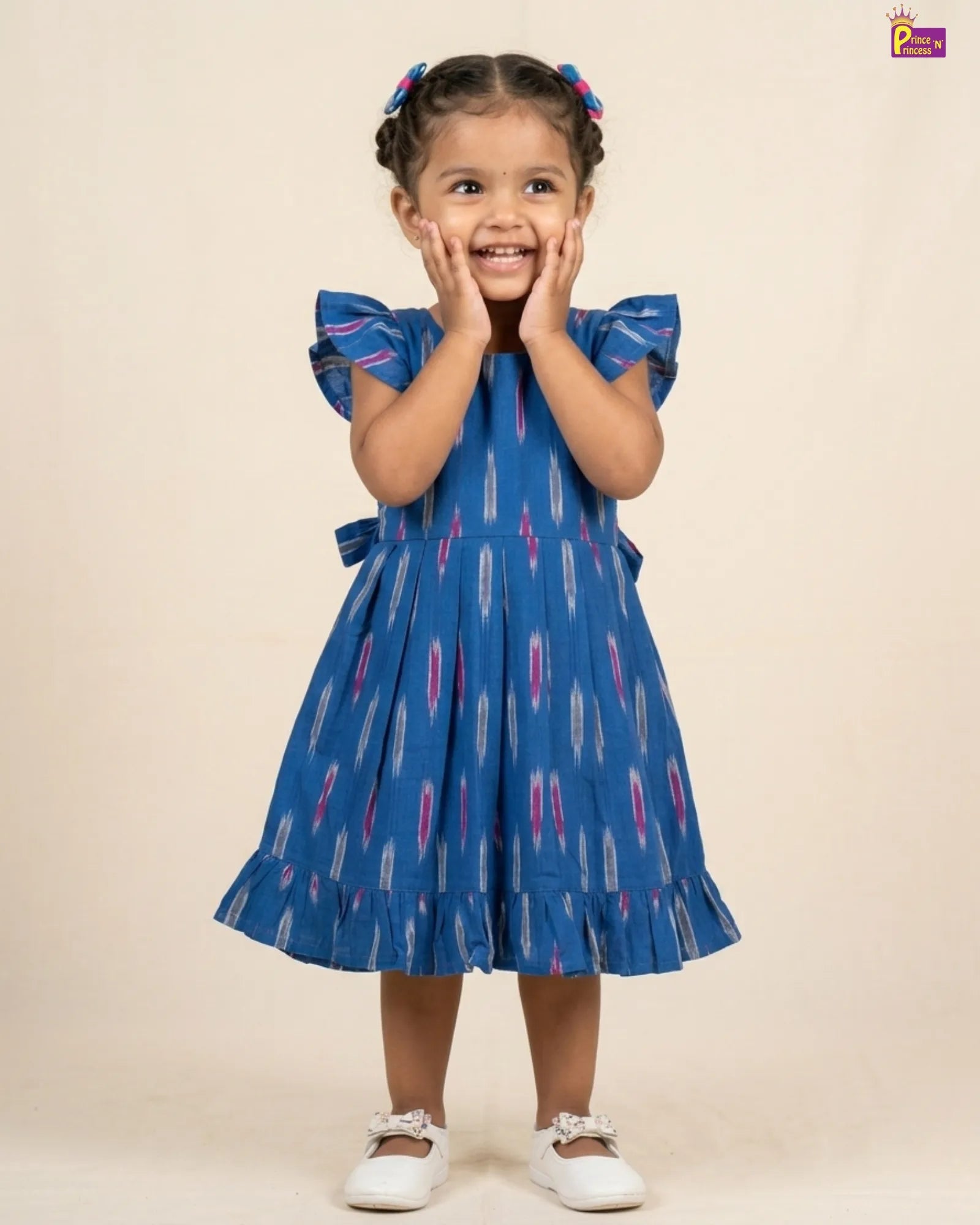 Child wearing a blue dress with a pattern on a beige background