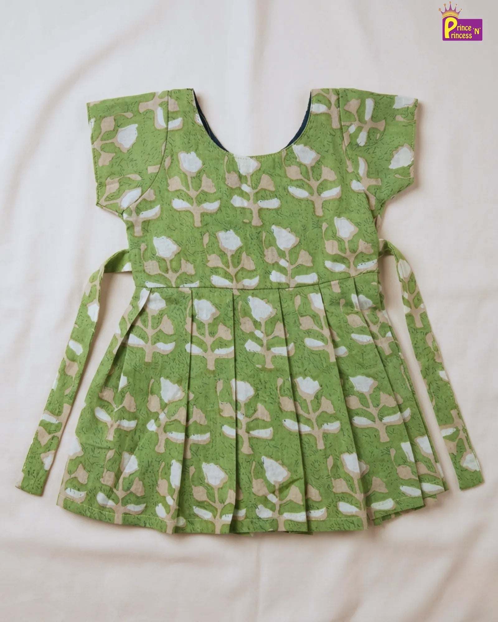 Green patterned blouse with pleated skirt on a white background