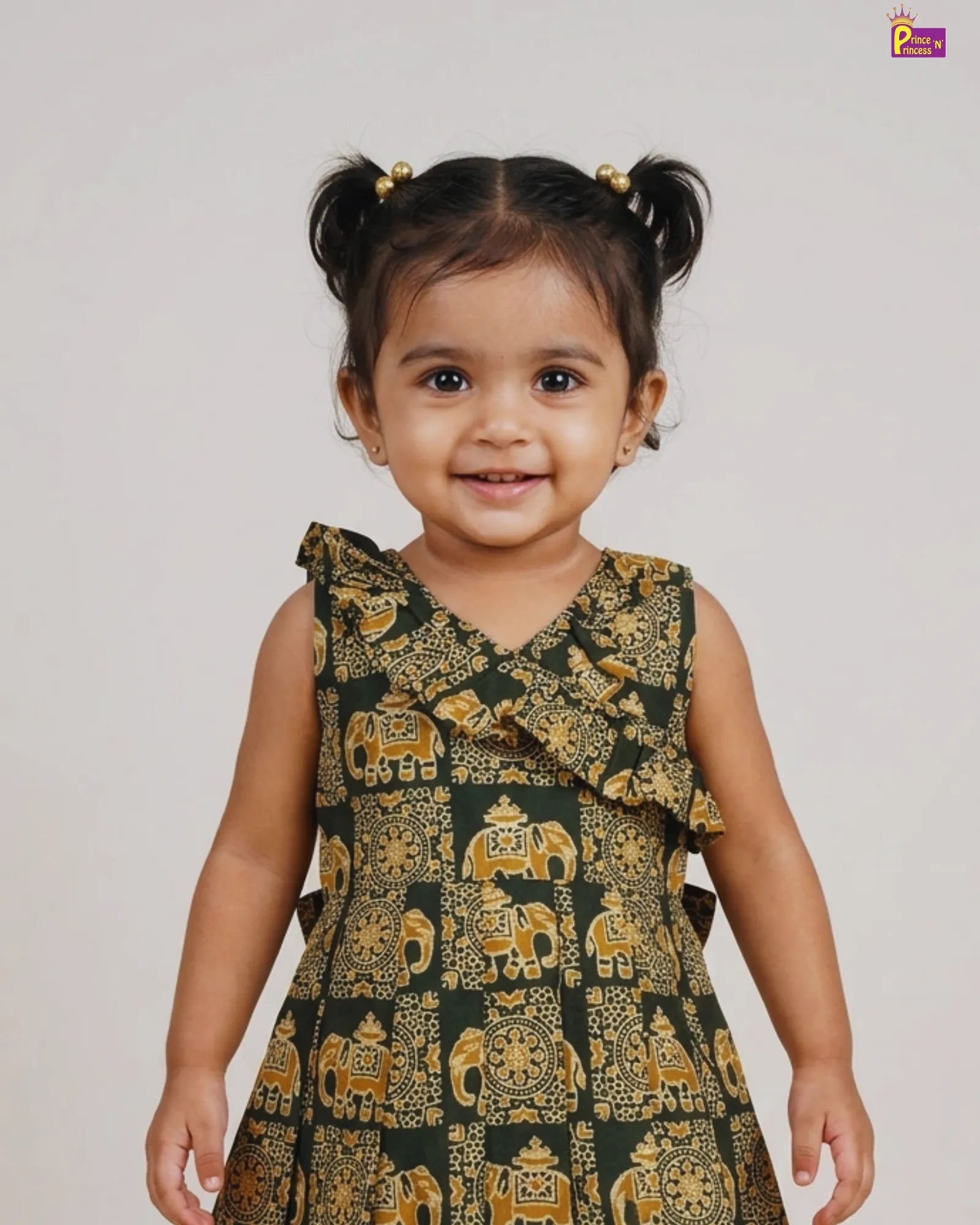 Child wearing a green dress with elephant patterns on a plain background