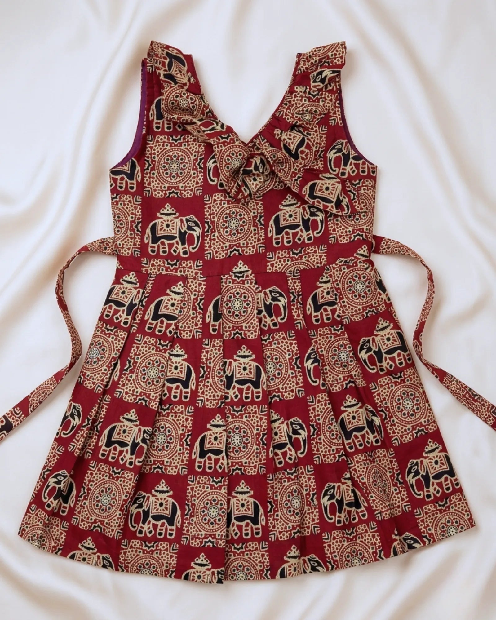 Red dress with elephant pattern on a white fabric background
