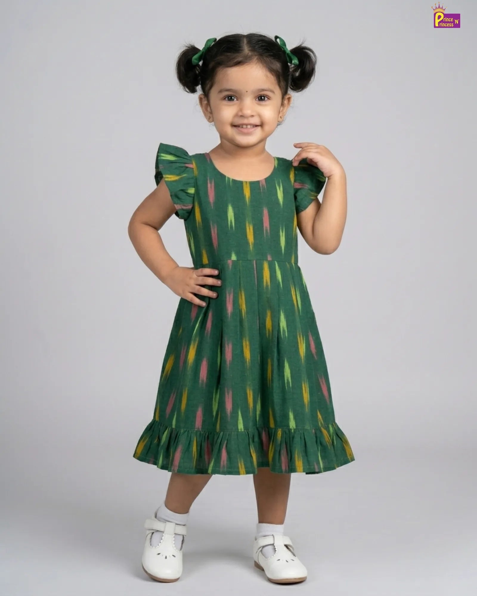 Child wearing a green dress with colorful patterns on a gray background