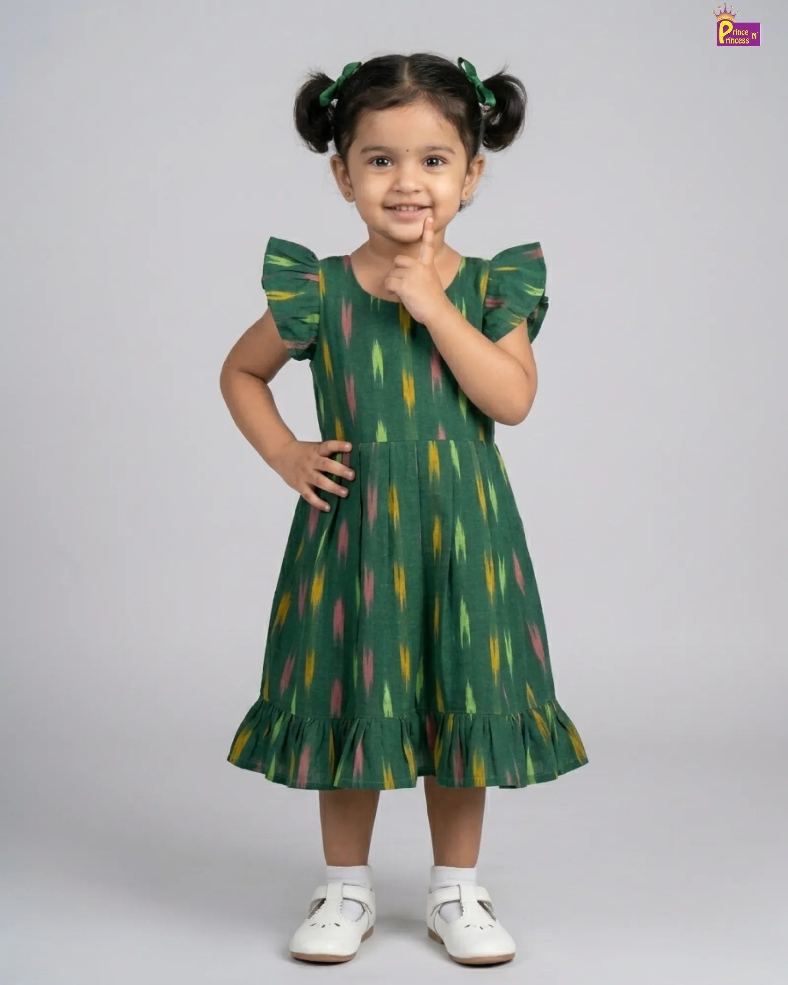 Child wearing a green dress with colorful patterns on a gray background