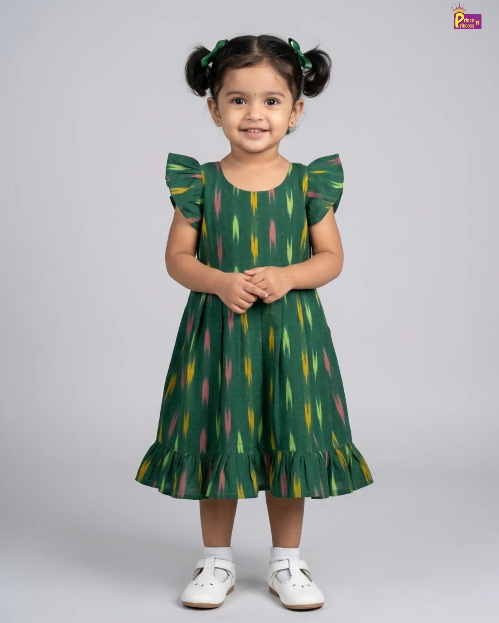 Young girl wearing a green dress with colorful feather pattern on a gray background