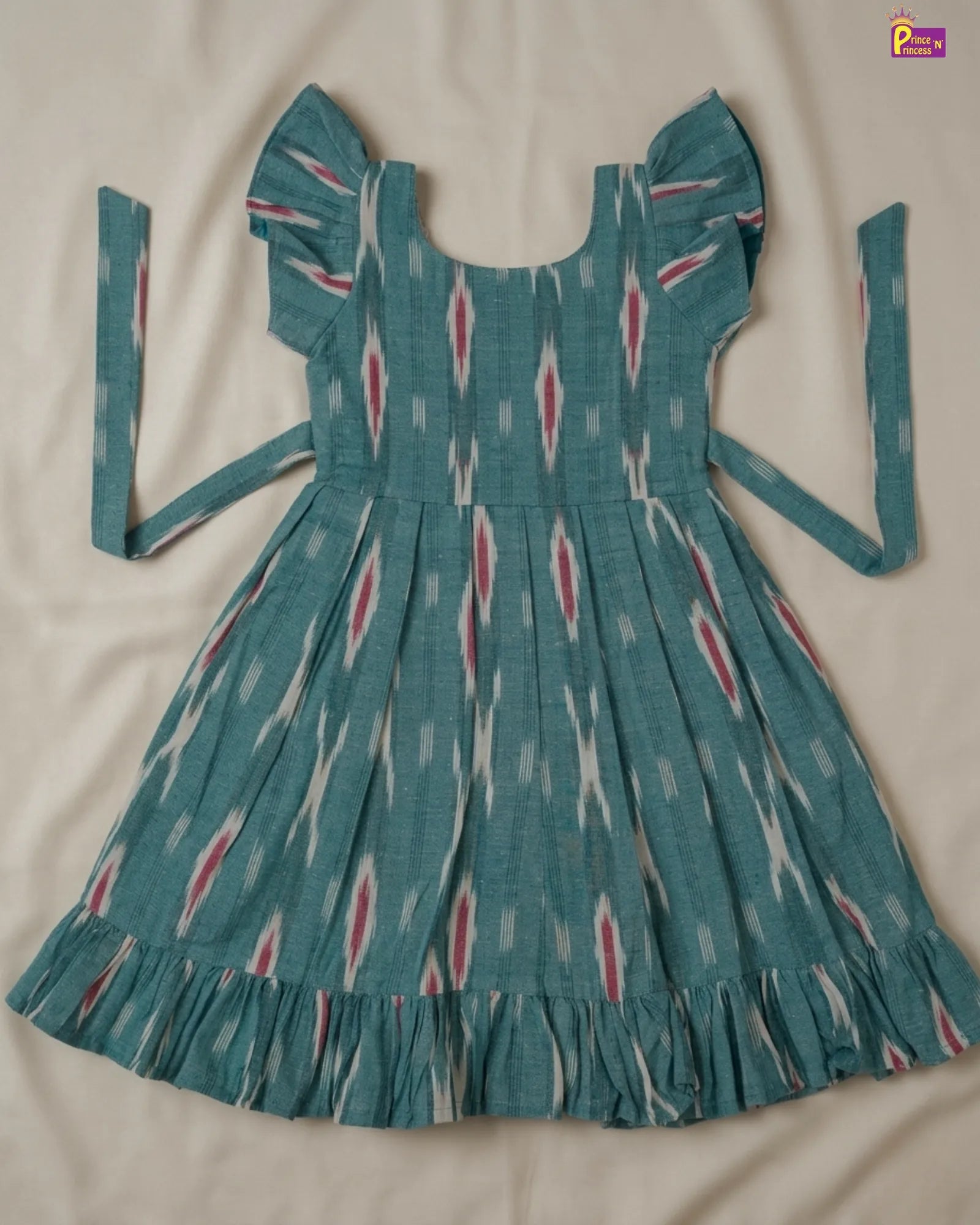 Teal dress with a pattern on a beige surface