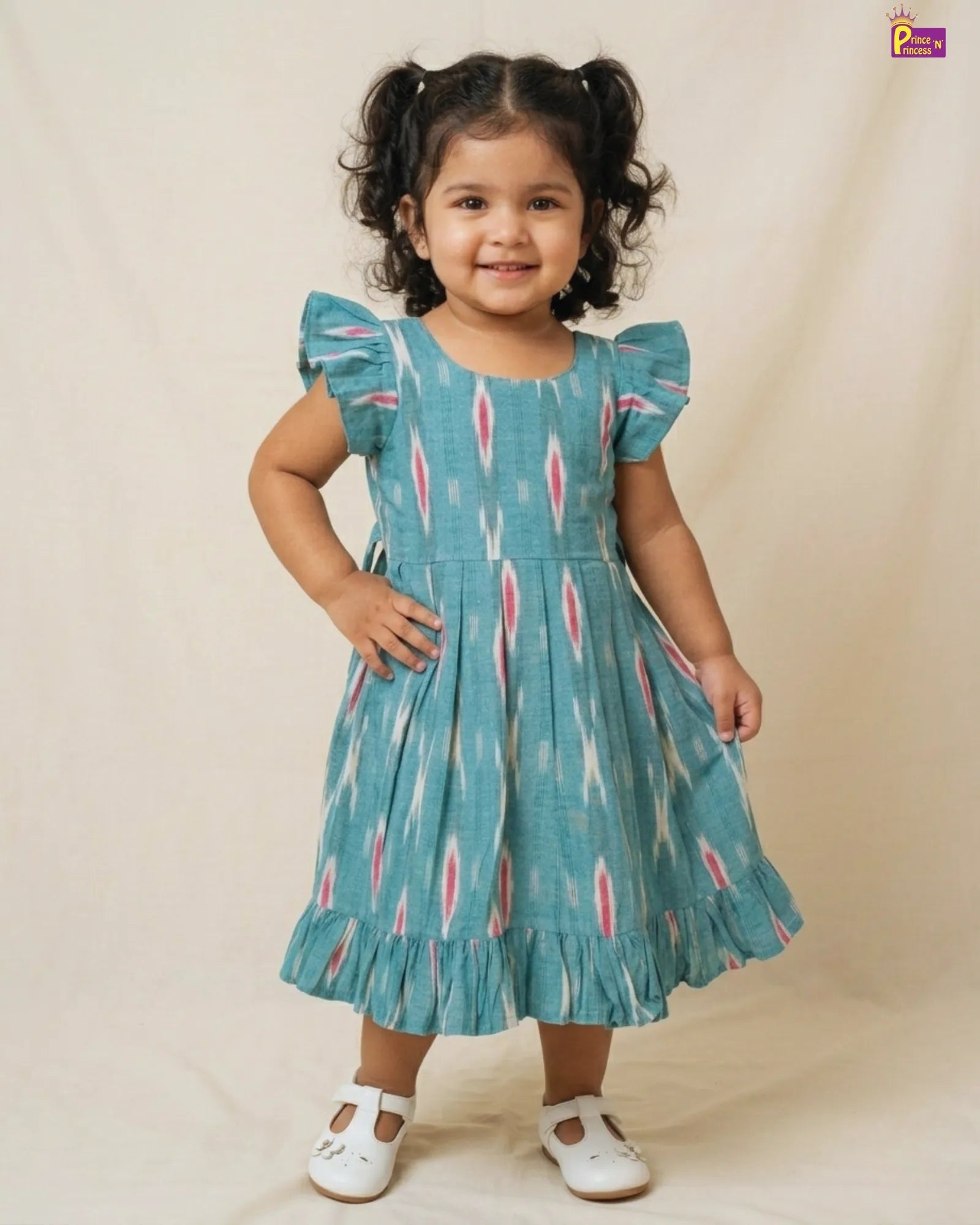 Young girl wearing a blue dress with pink patterns on a beige background
