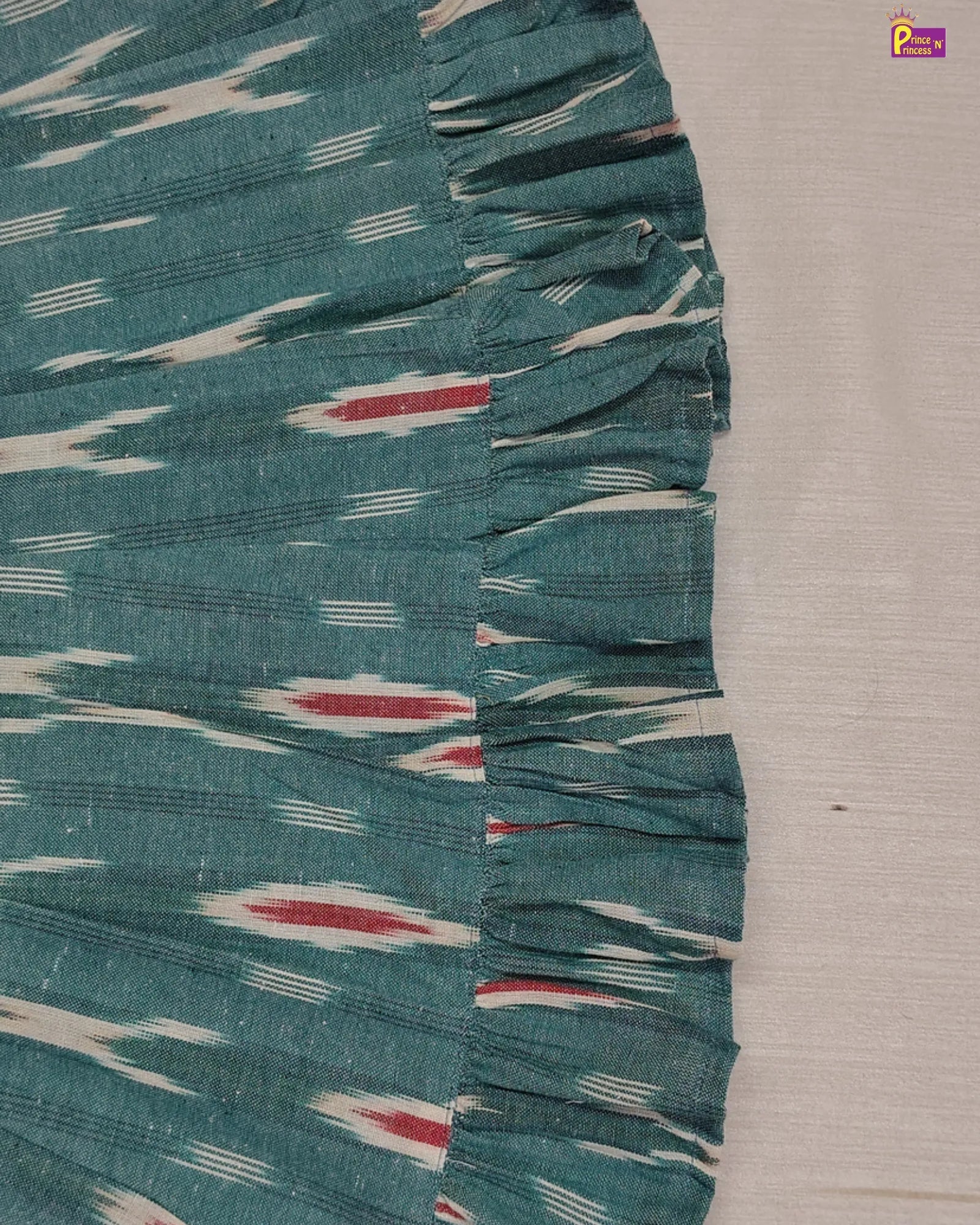 Teal fabric with white and red patterns on a gray background