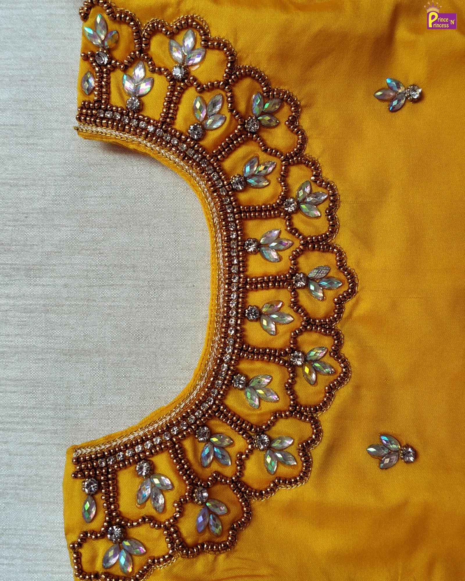 Close-up of a yellow fabric with intricate silver embroidery on a light gray background