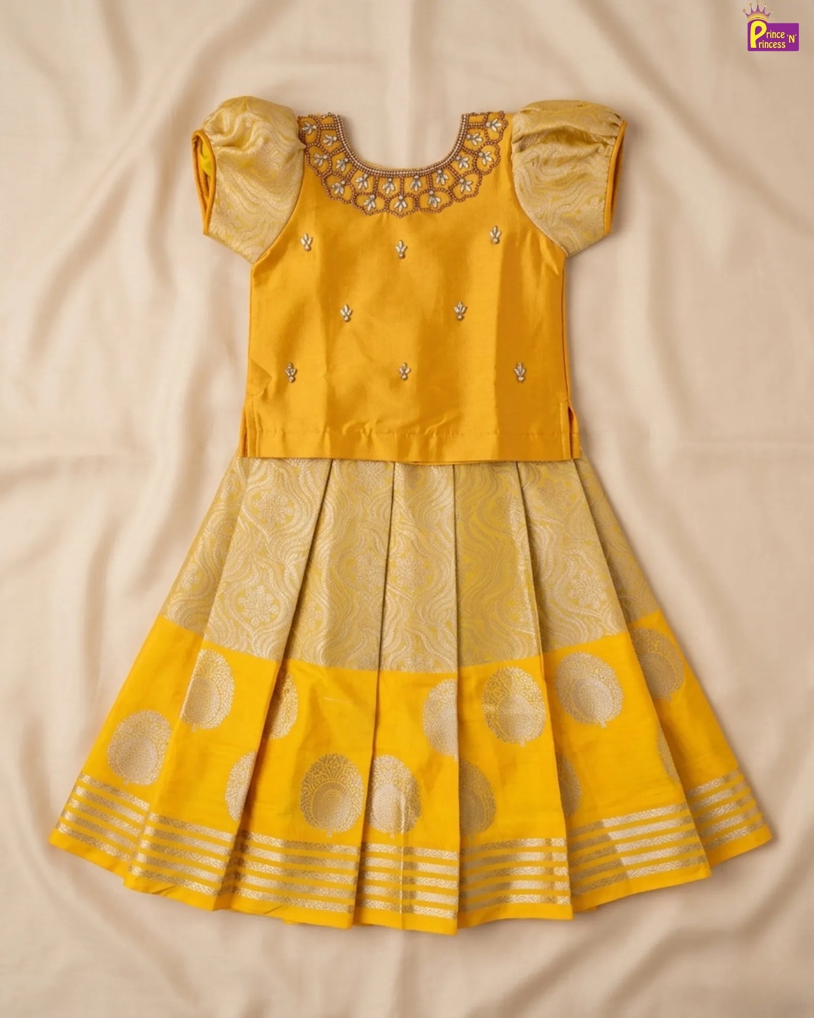 Yellow traditional outfit with intricate designs on a beige fabric background